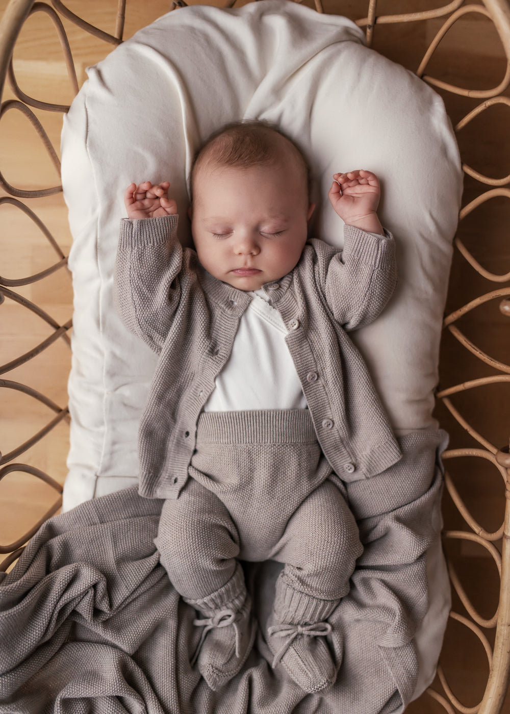 Sælger baby i beige strikket sæt liggende i kurv