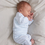 Lyseblå langærmet babybody på barnet med lange ben og trykknapper