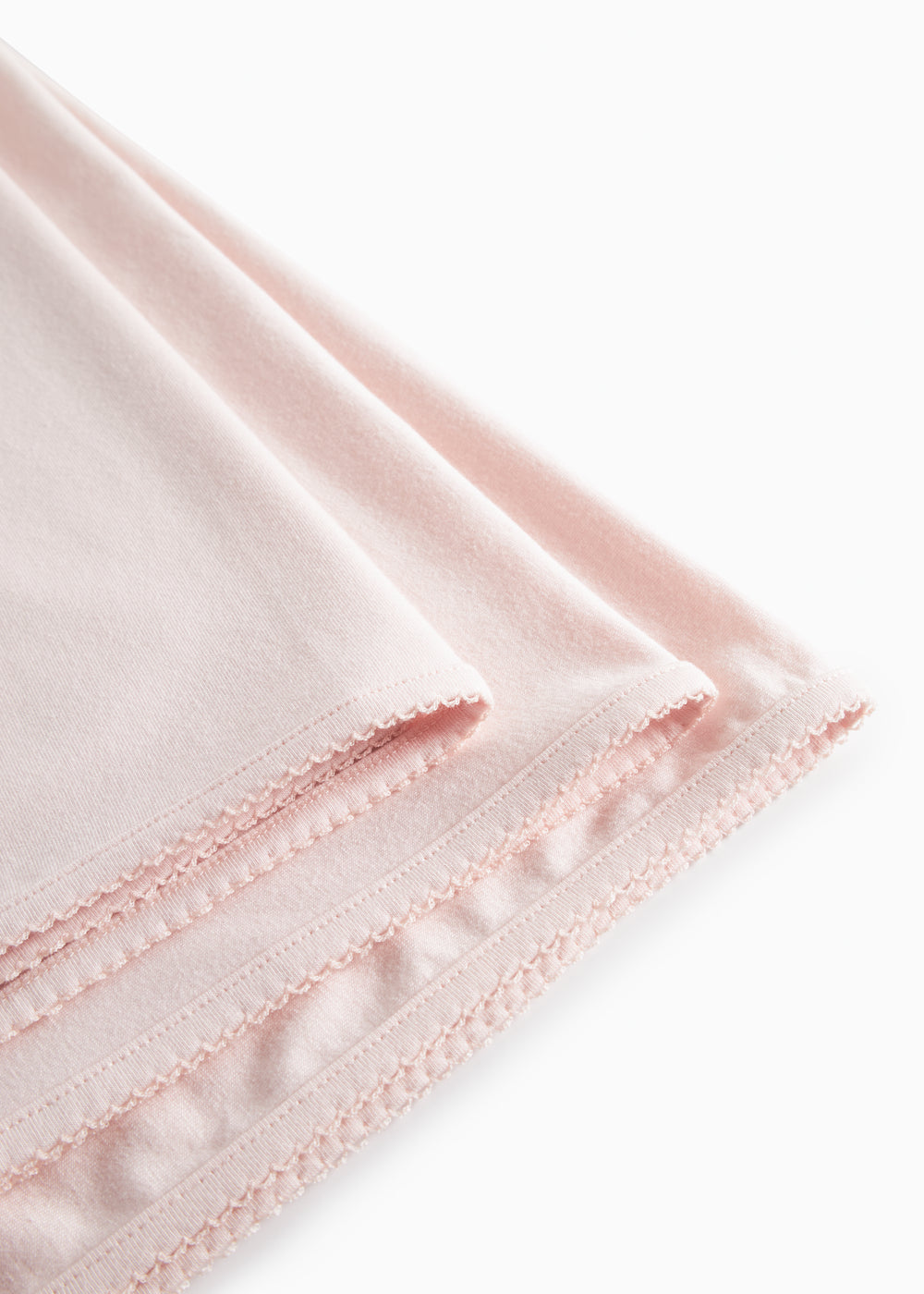 Lyserødt babytæppe med dekorativ stikning og frynsekant langs kanten