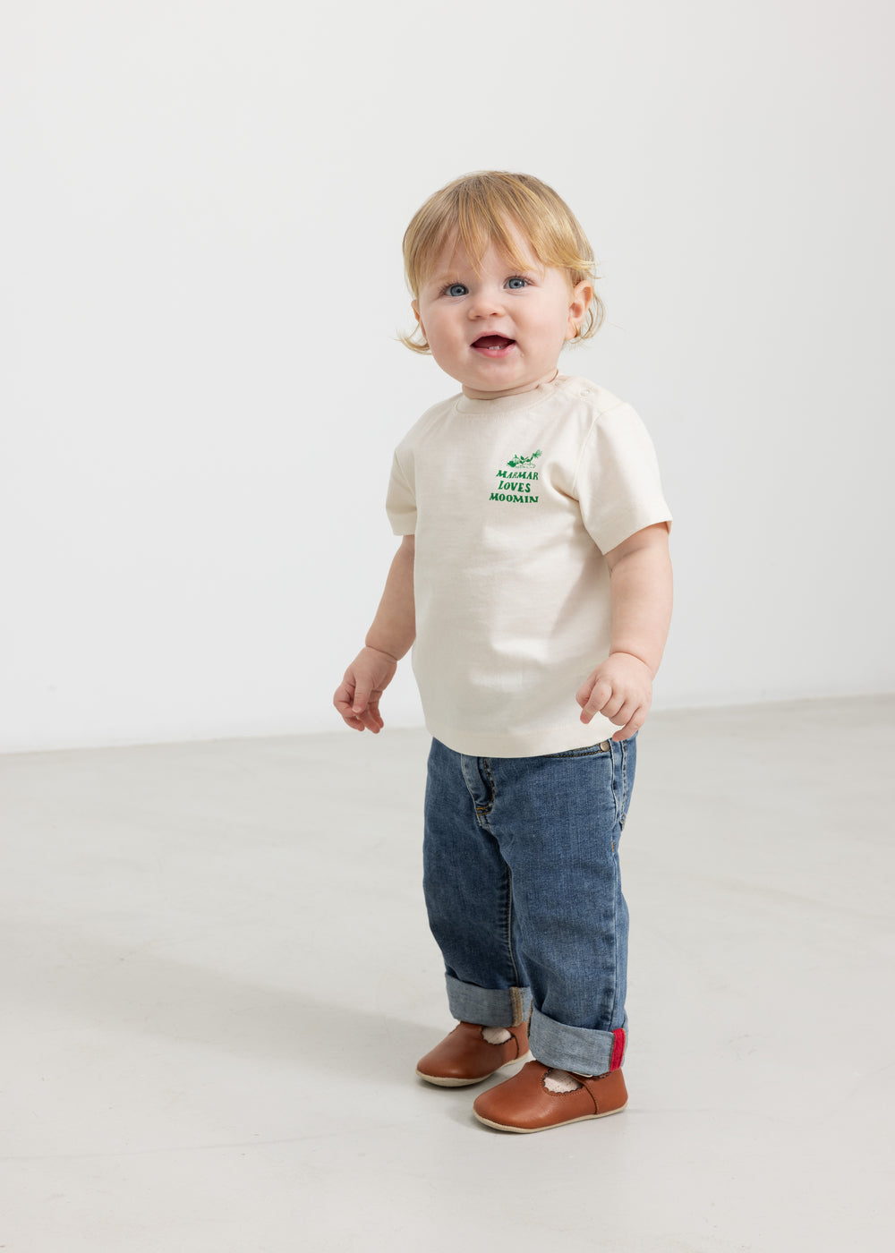 Baby iført råhvid T-shirt med grønt Moomin print og jeans