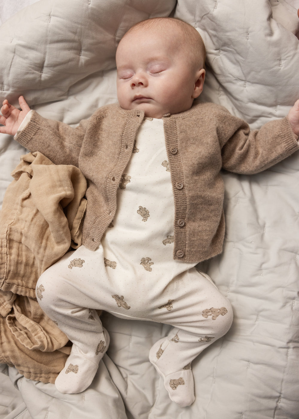Heldragt til baby i hvid med beige teddybjørn-print, synlig med lange ben