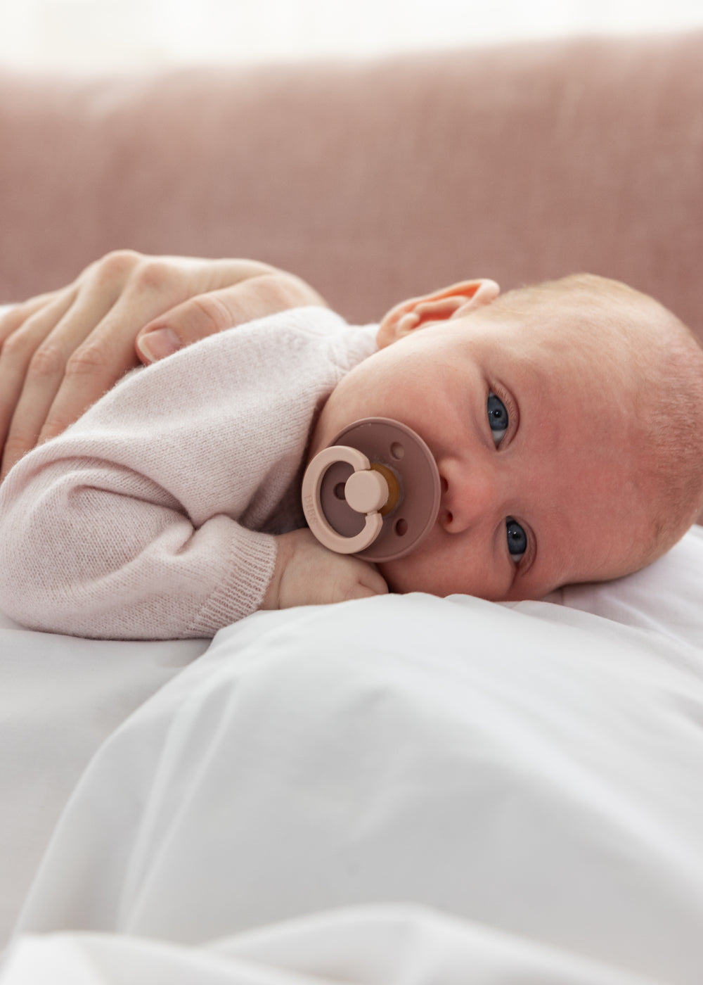 Lyserød cardigan på baby med knapper fortil og bløde, strikkede ribkanter.