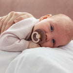 Lyserød cardigan på baby med knapper fortil og bløde, strikkede ribkanter.