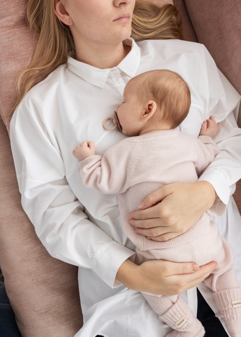 Rosa melerede strikkede babysko på babyfødder, med snørebånd