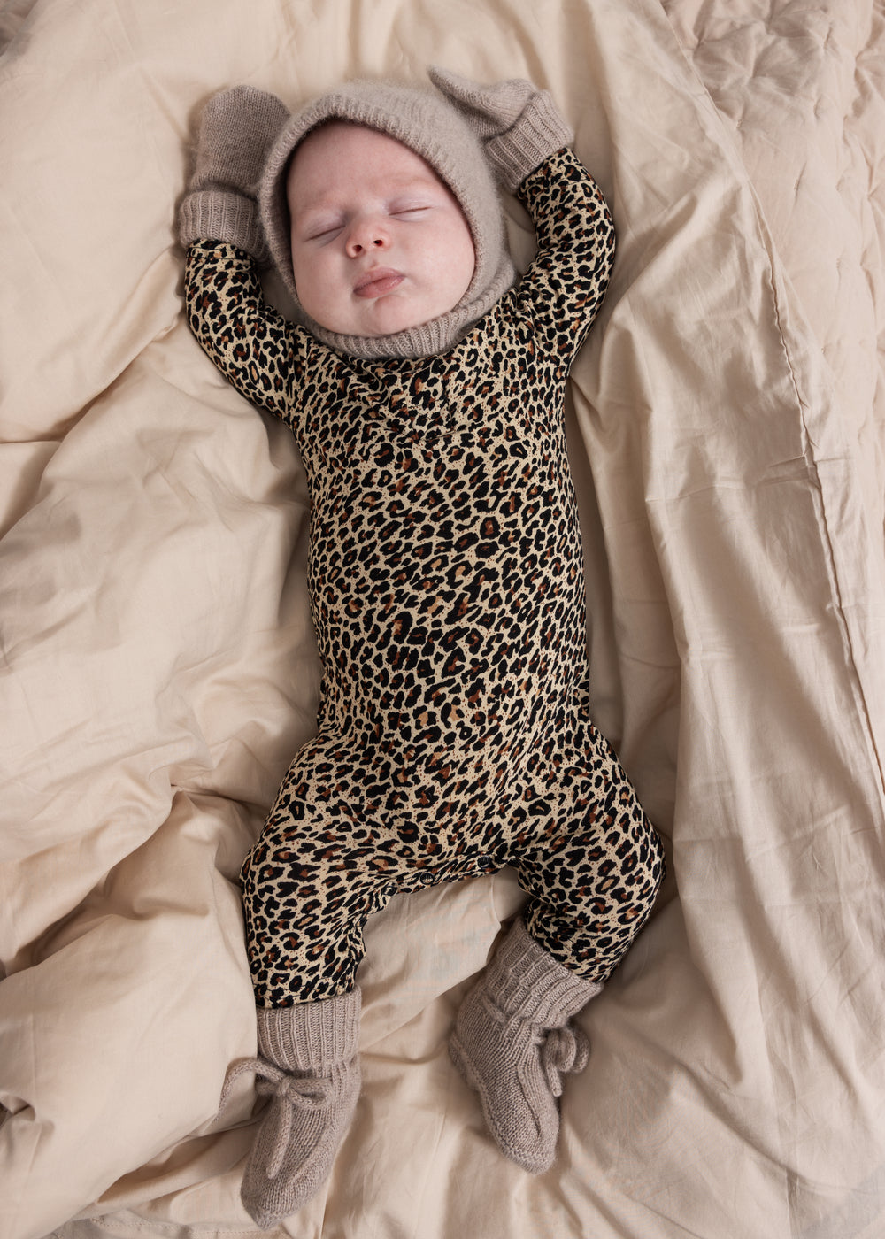 Strikkede babysokker på babyfødder i grå-beige melange med ribkant og sløjfe
