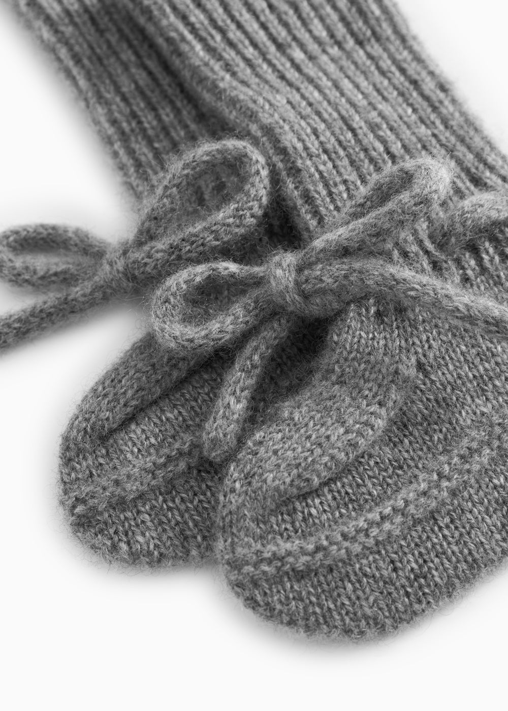 Nærbillede af grå strikket babybootie med sløjhedetalje over ribkant