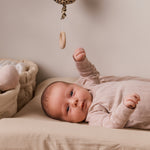 Leopardmønstret musikuro over sengen; baby i lys beige heldragt