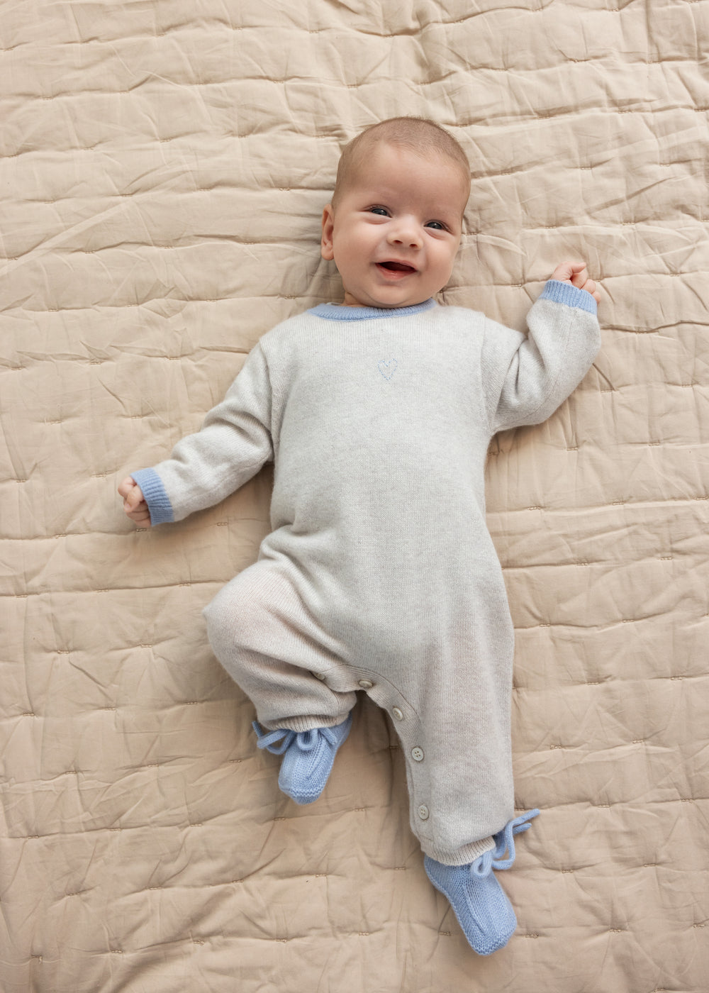 Beige babyheldragt i strik med blå krave, lange ærmer og knaplukning ved ben