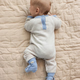 Beige babyheldragt med blå krave og knapbånd, set bagfra på baby