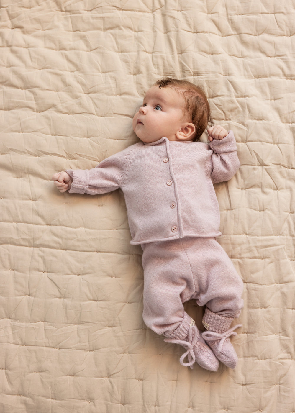 Baby iført lyse blommefarvet cardigan med knapper foran og lange ærmer