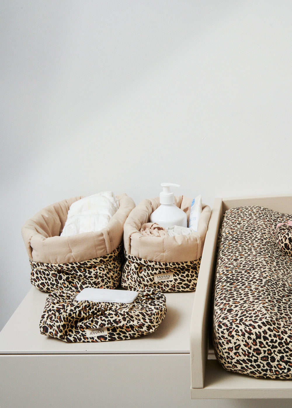 Opbevaringskurve i brunt leopardmønster med lyse indvendige kanter på hylde
