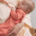 Baby-pyjamas i lys beige med orange kant, knapper og stribede shorts/bukser