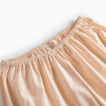 Beige pyjamasbukser med elastisk linning og orange piping ved benkanten