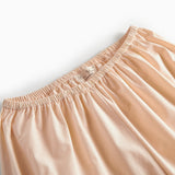 Beige pyjamasbukser med elastisk linning og orange piping ved benkanten