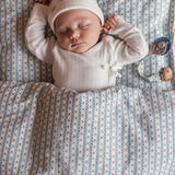 Baby i hvid heldragt med suttesnor hængende ved øverste hånd