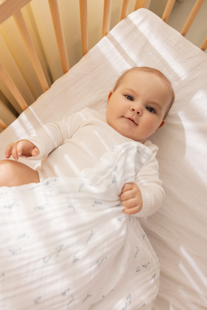 Babysengetøj i hvidt med små delfiner i blå og grønne detaljer