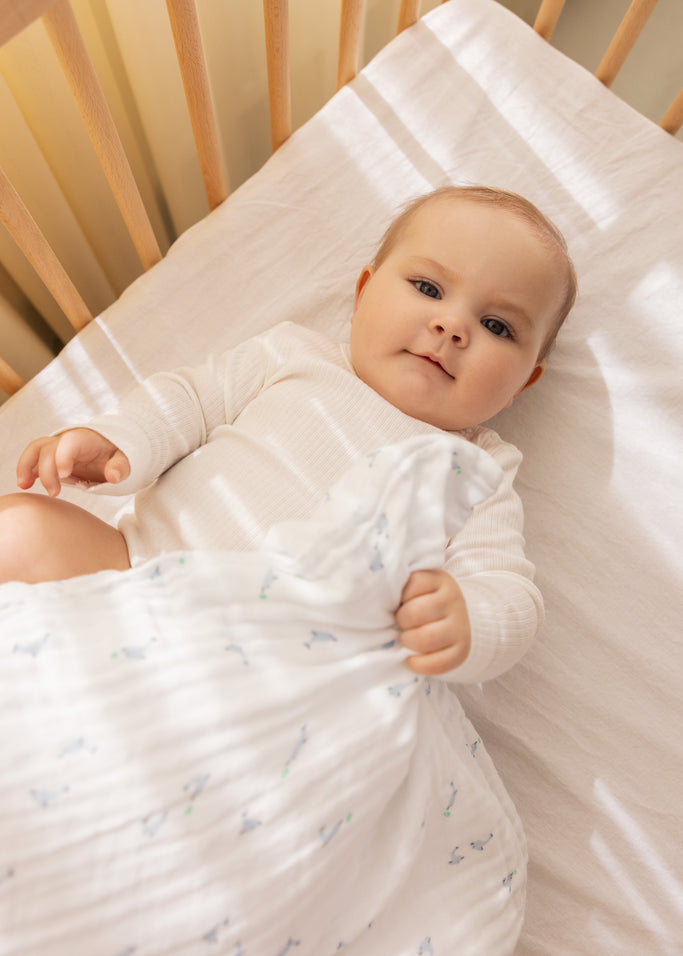 Babysengetøj i hvidt med små delfiner i blå og grønne detaljer