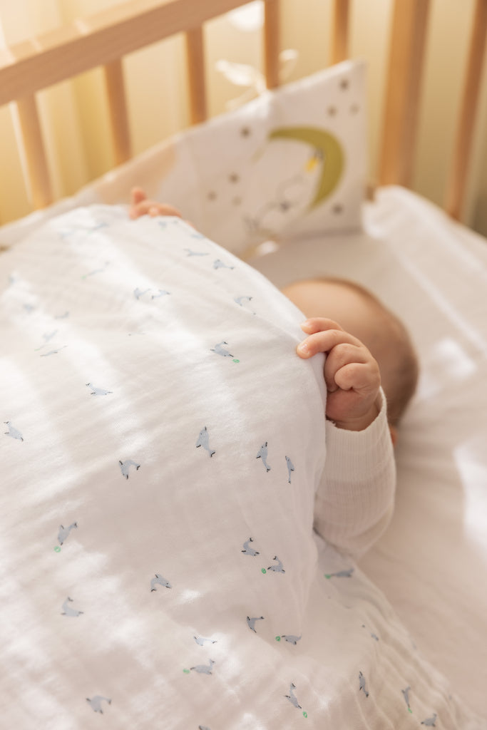 Babysengetøj i hvidt med små delfinprint i blå og grønne nuancer