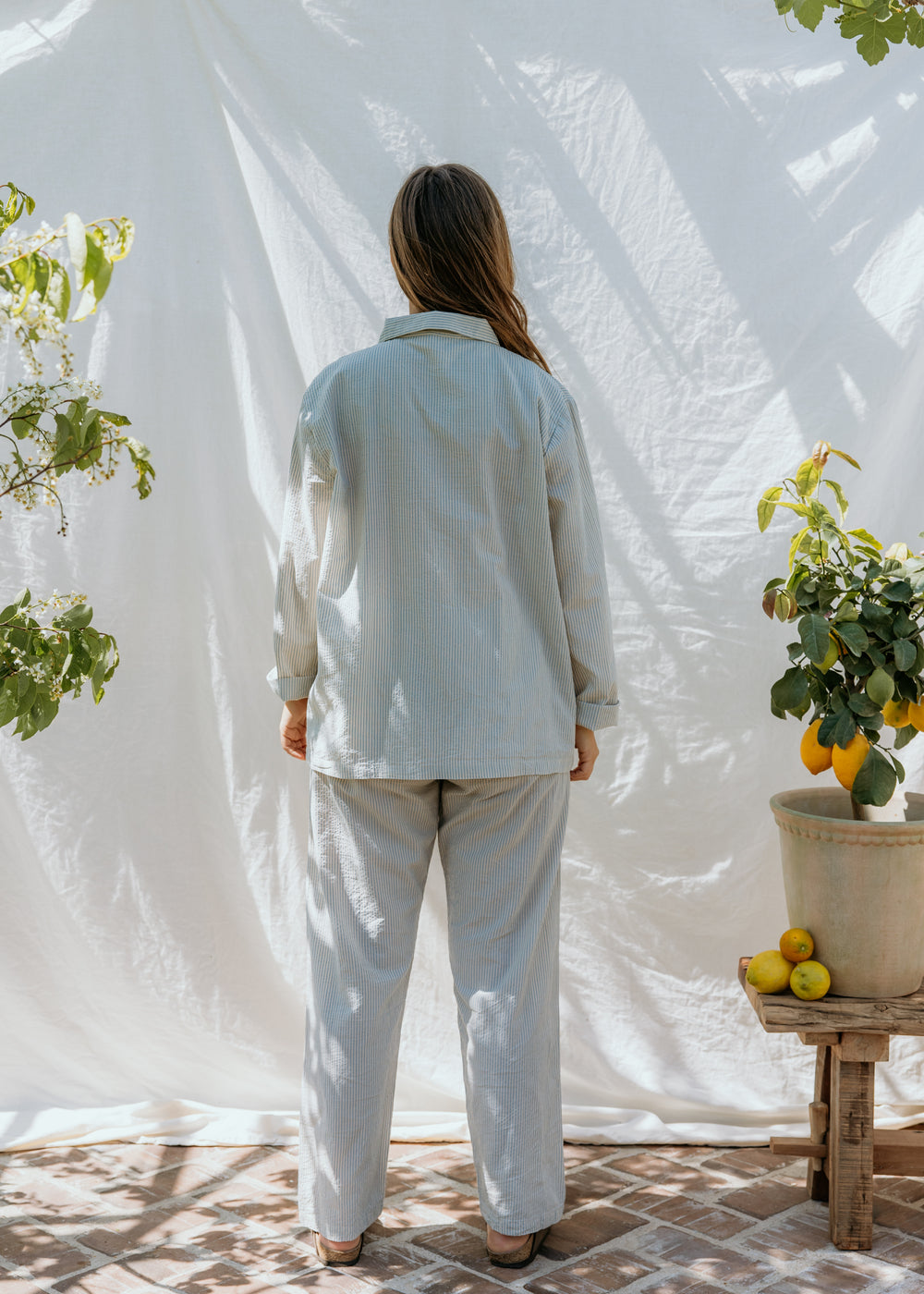 Lyseblå stribet pyjamasæt set bagfra: langærmet skjorte og bukser med elastik