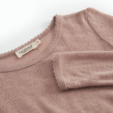 Detalje: rosa uld pointelle-T-shirt med rund hals og mærke i nakken.