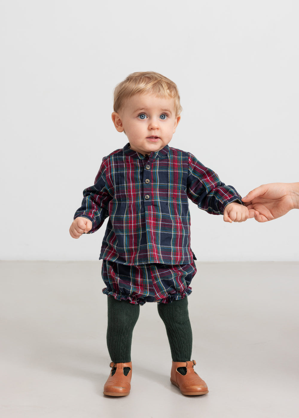Baby iført mørkeblå og rød ternet skjorte og bloomers