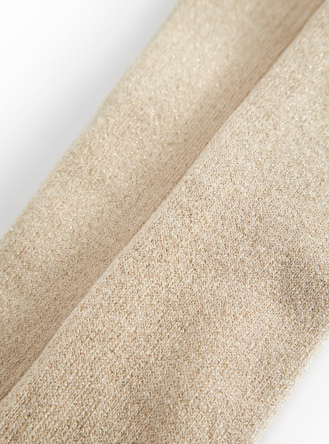 Detalje af beige strømpebuksstof med fin guldsparkle og glitrende tekstur