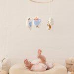 Babymobil med Moomin-figurer ophængt i ring over babypude.