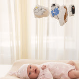 Babymobil med Moomin-figurer ophængt i stof, set over babys seng.