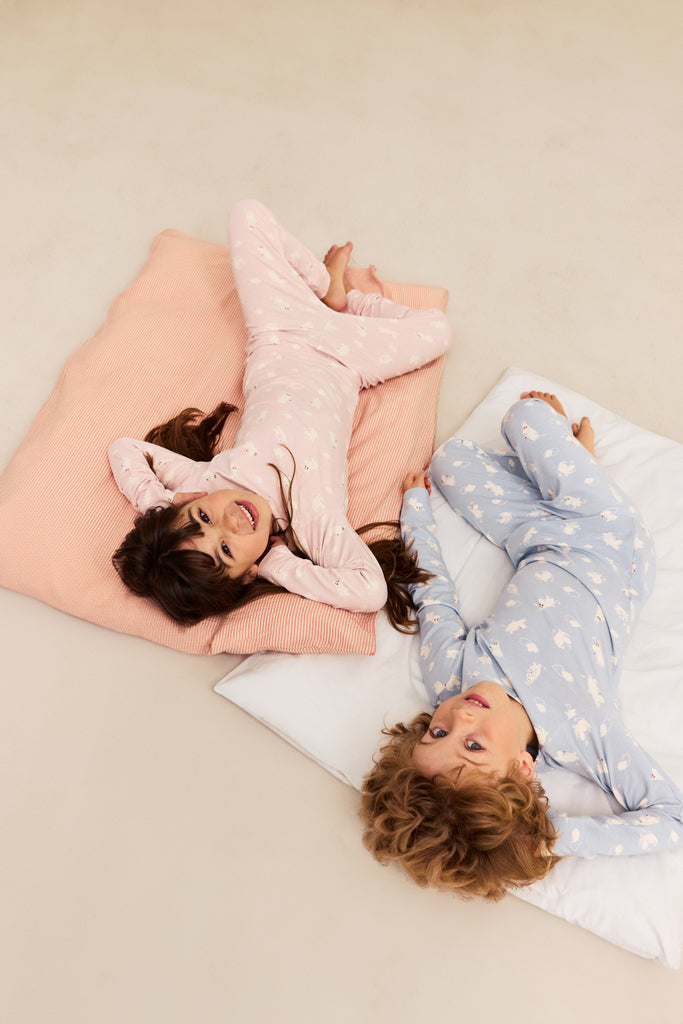 Børnepyjamas i lyseblå og lyserød med lange ærmer og heldragt-lignende mønster
