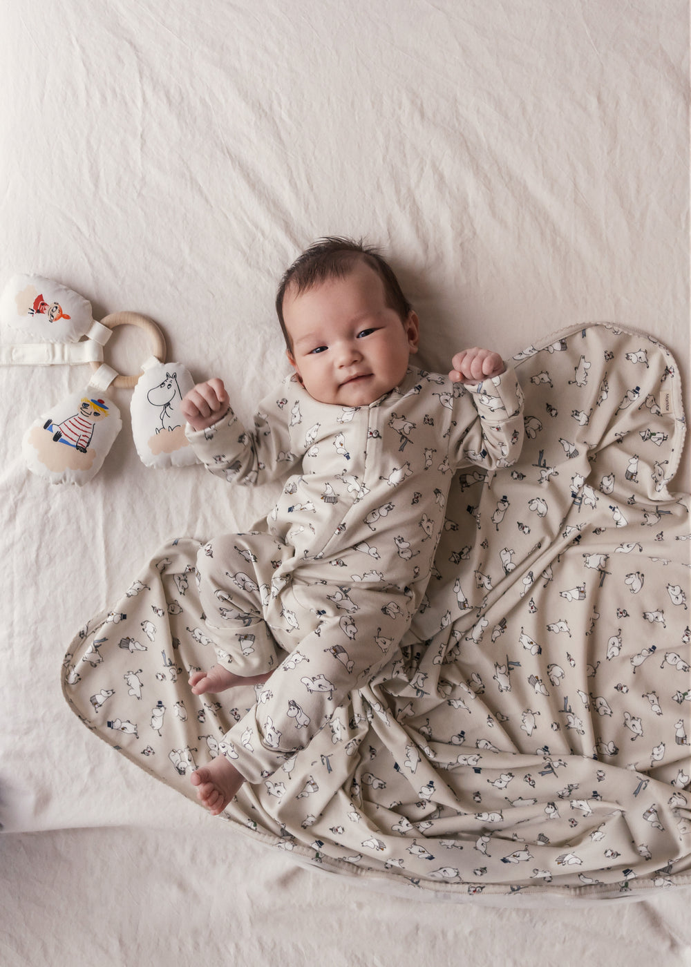 Baby ligger på baby tæppe med Moomin-print.