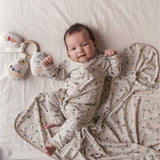 Baby ligger på baby tæppe med Moomin-print.