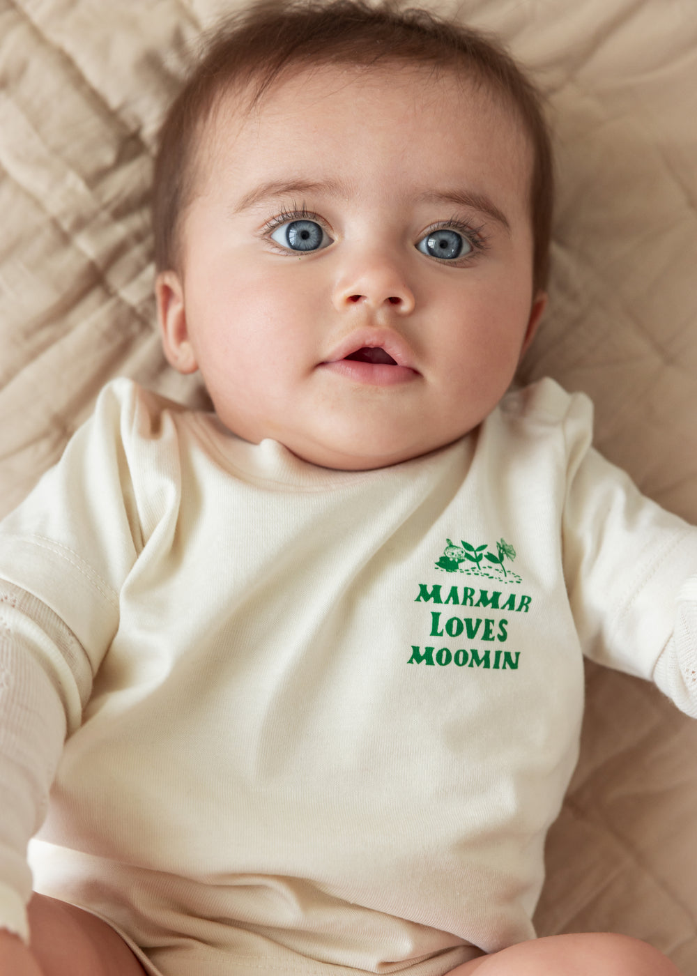 Baby iført råhvid t-shirt med grønt Moomin print