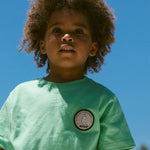 Børne-T-shirt i mintgrøn med rund hals og lille rund patch på brystet