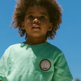 Børne-T-shirt i mintgrøn med rund hals og lille rund patch på brystet