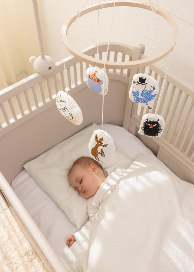 Babymobil til tremmeseng med hængende Moomin-figurer over babys seng.