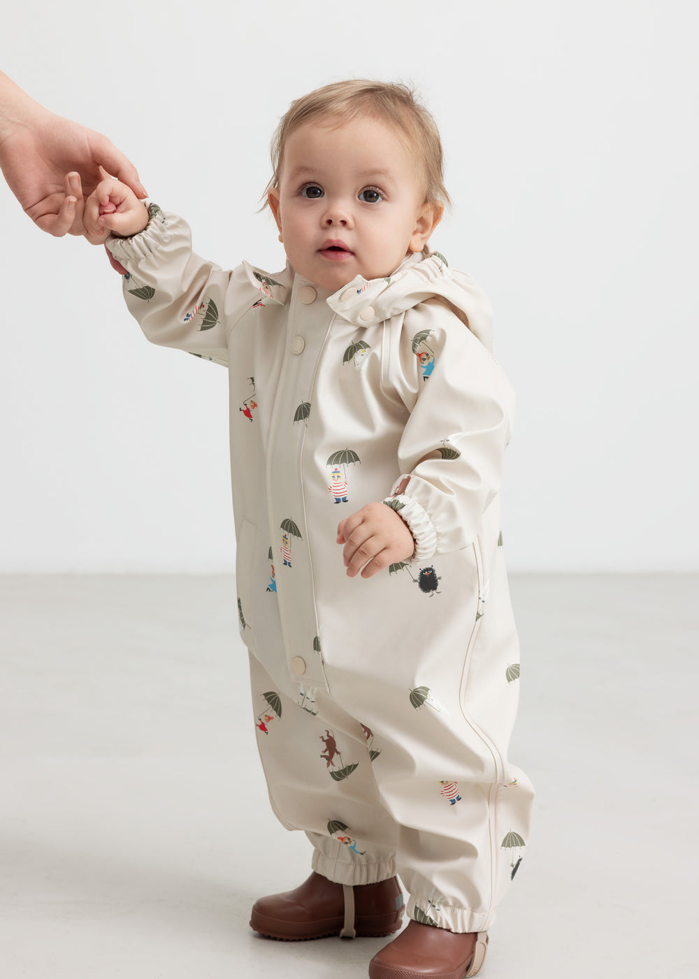 Baby iført beige regndragt med Moomin print og hætte