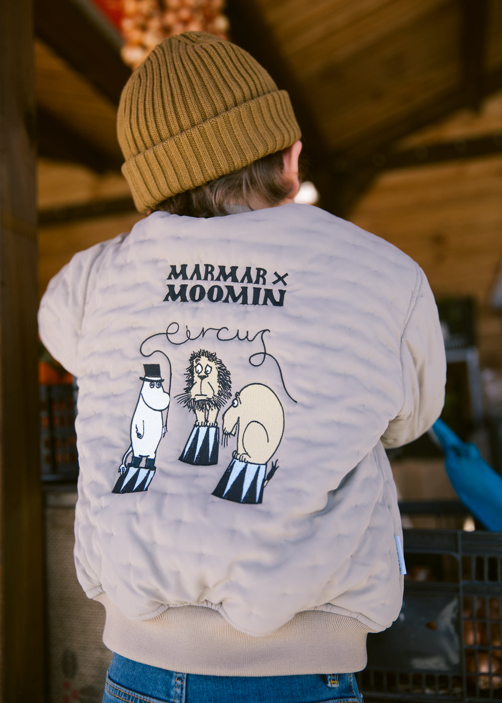 Barn set bagfra iført grøn jakke med Moomin print og brun hue