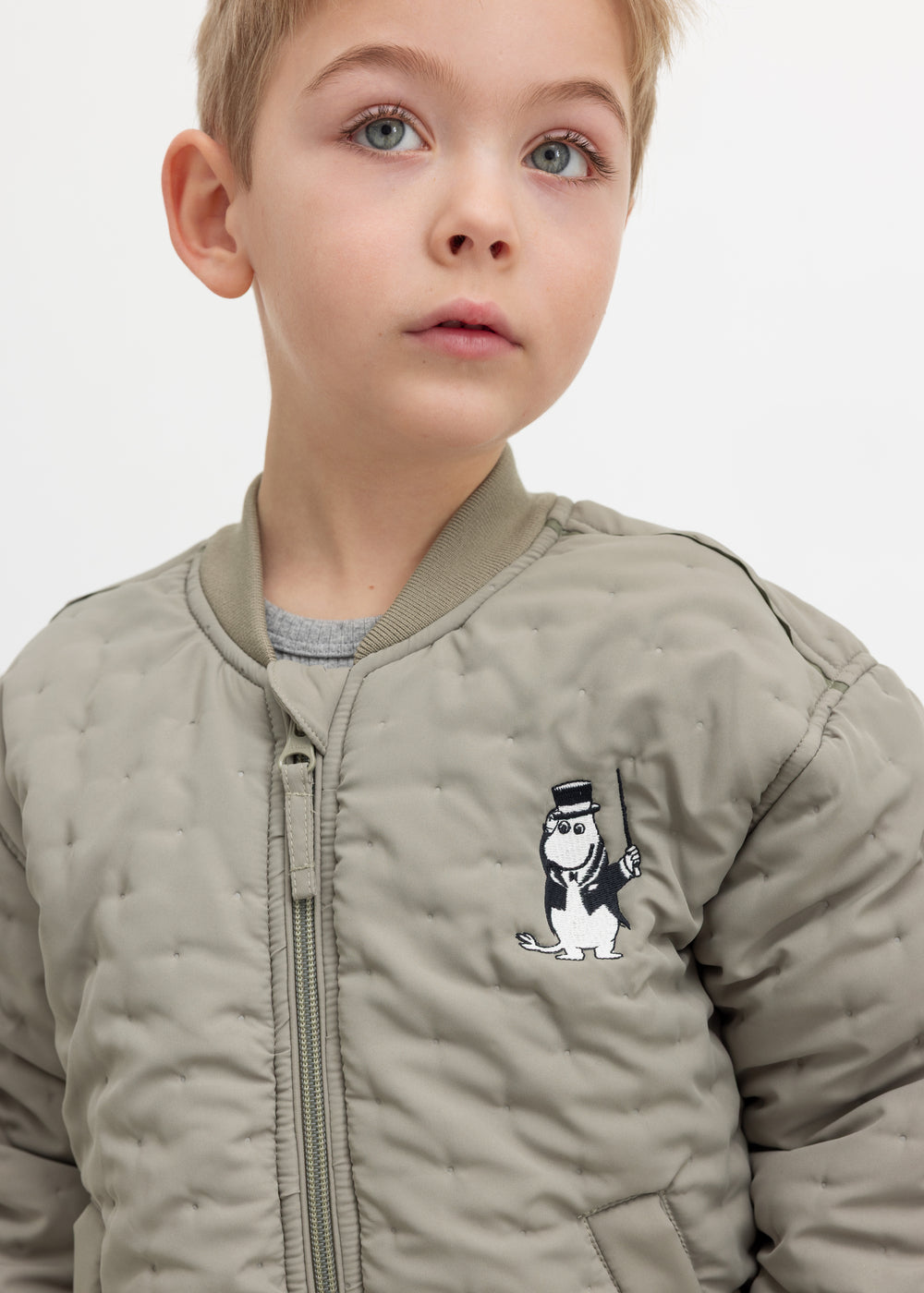 Barn iført grøn quiltet jakke med Moomin print