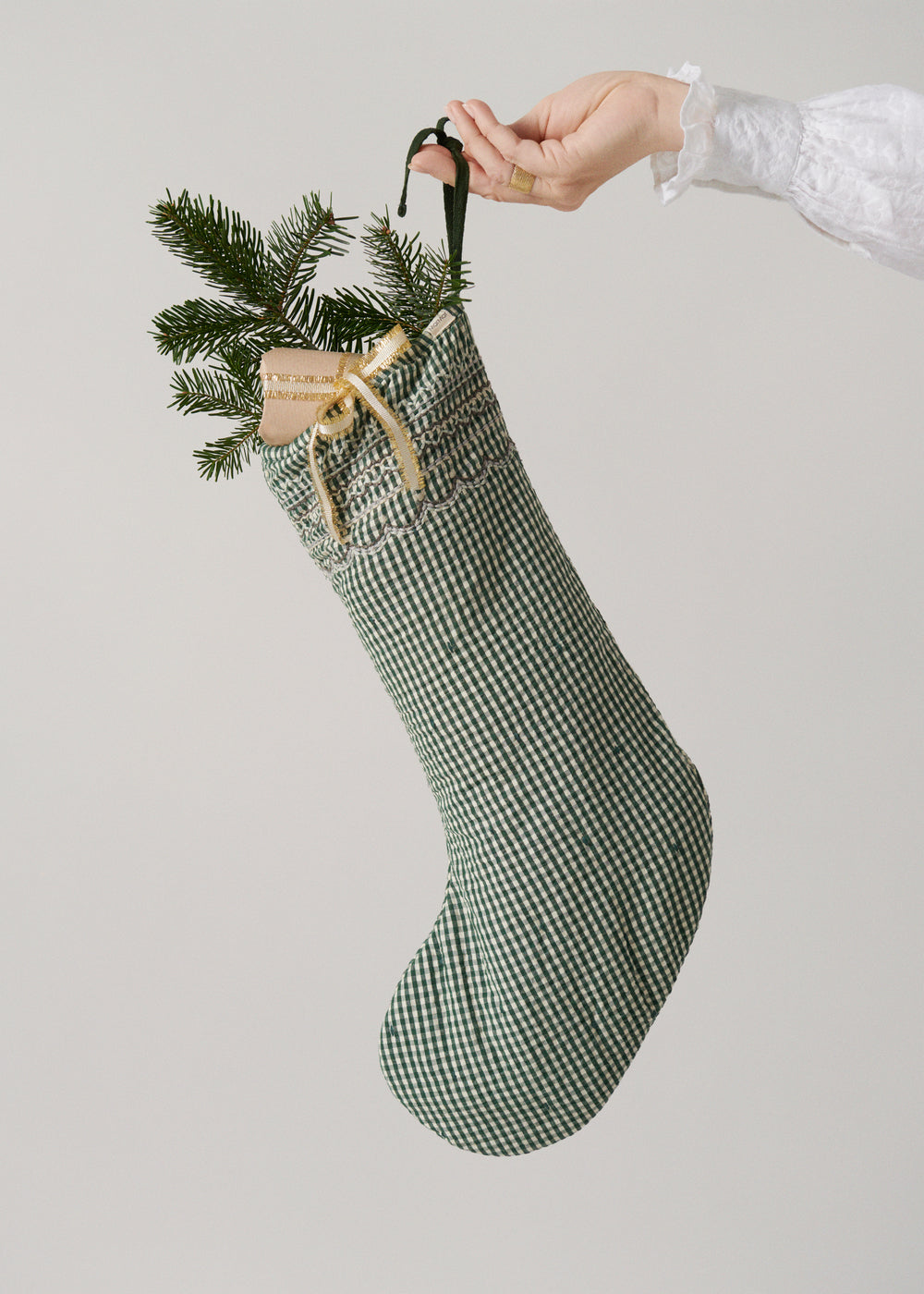 Grønternet julesok med pinegren og beige dekorationspose ved ophænget