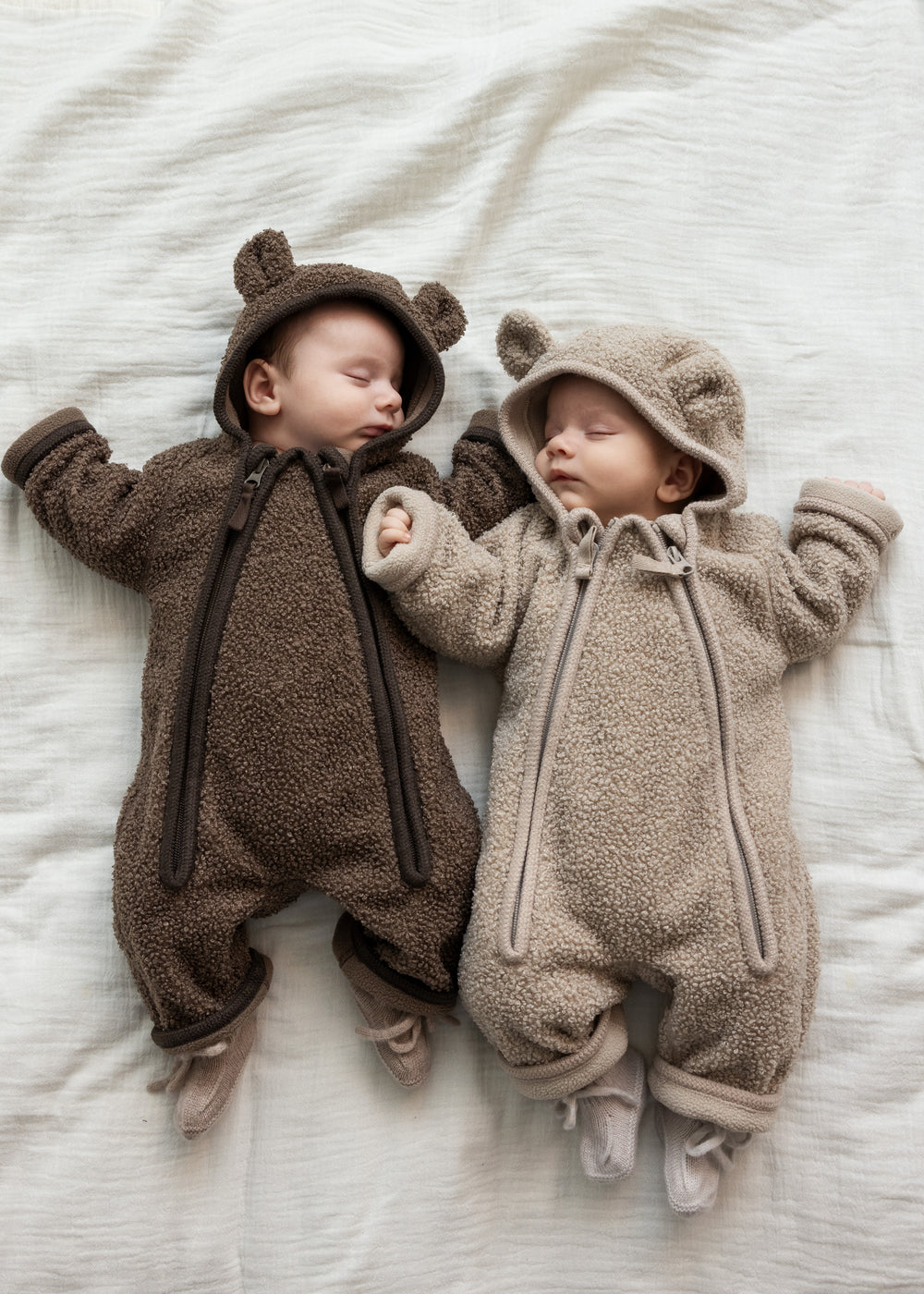 For babyer iført teddyheldragter, den ene i lys beige og den anden i brun