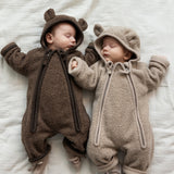 For babyer iført teddyheldragter, den ene i lys beige og den anden i brun