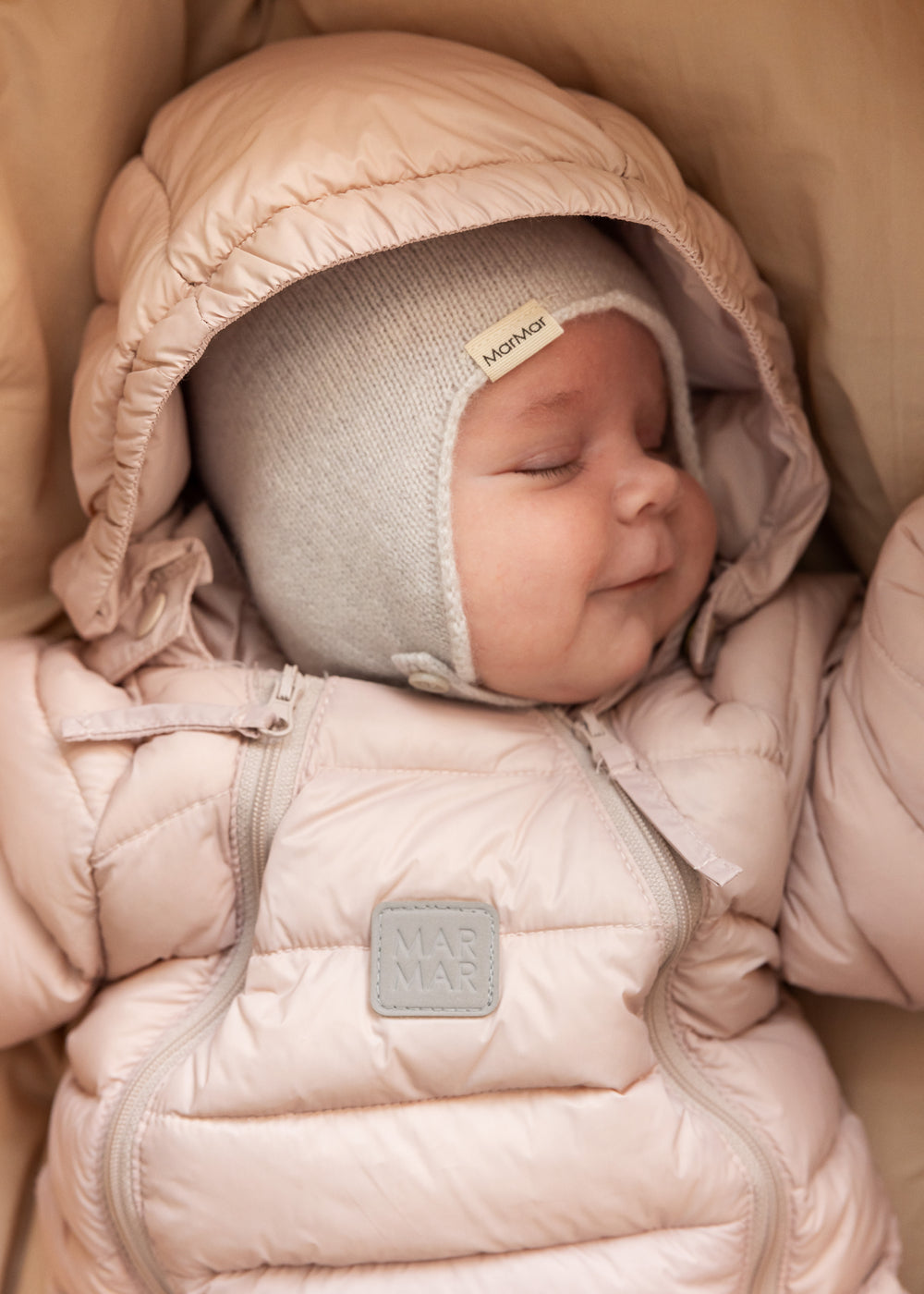 Baby iført lyserød dundragt og strikket hat