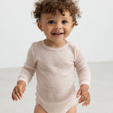Baby iført lyserød body i merinould