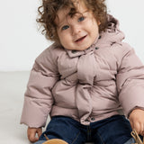 Let plum dunjakke til børn med hætte og lynlås, båret af model.