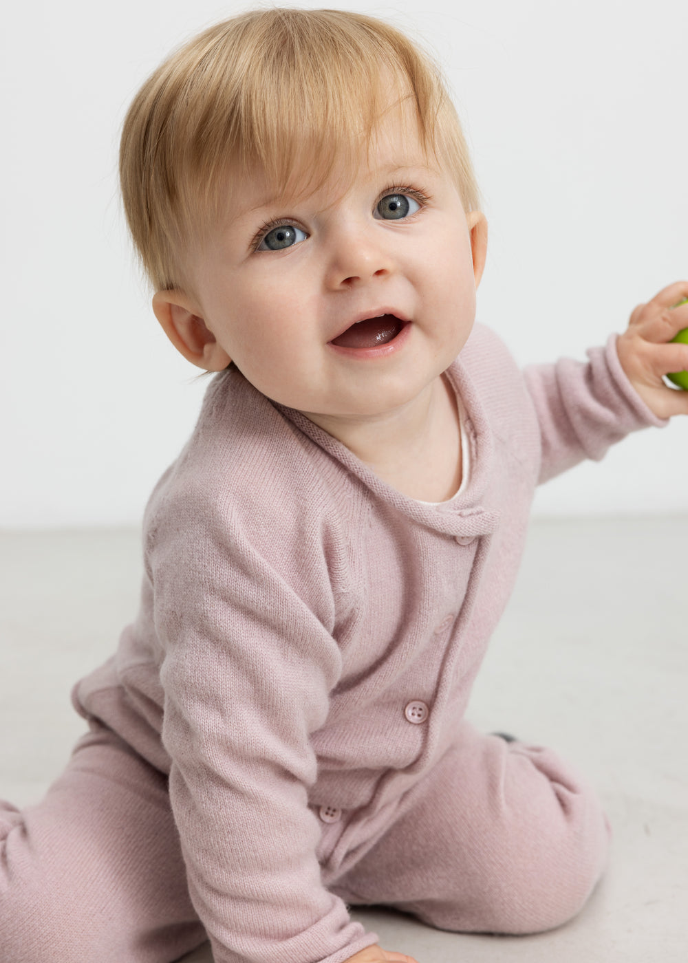 Lyse blommefarvet babys cardigan med knaplukning ved halsen og lange ærmer