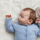 Lyseblå cardigan med knaplukning på baby, rund hals og lange ærmer i bevægelse