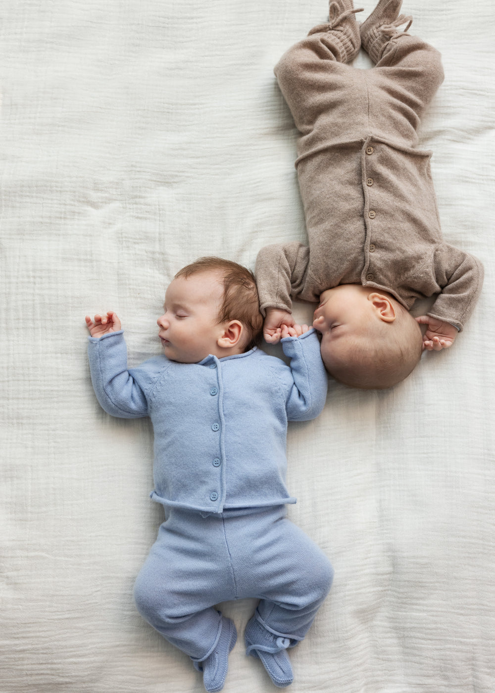 Lyseblå babycardigan med knaplukning og lange ærmer, båret af spædbørn