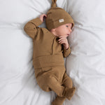 Baby med brun ribstrikket body med knapper foran og babyhue