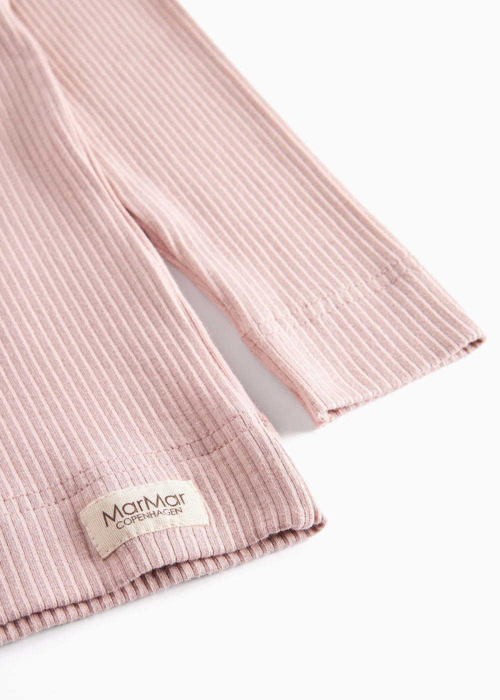 Detaljer af ribstrikket nederste kant på rosa børnetøj