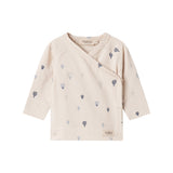 Børnebluse med lange ærmer i creme med små blå balloner og slå-om detalje